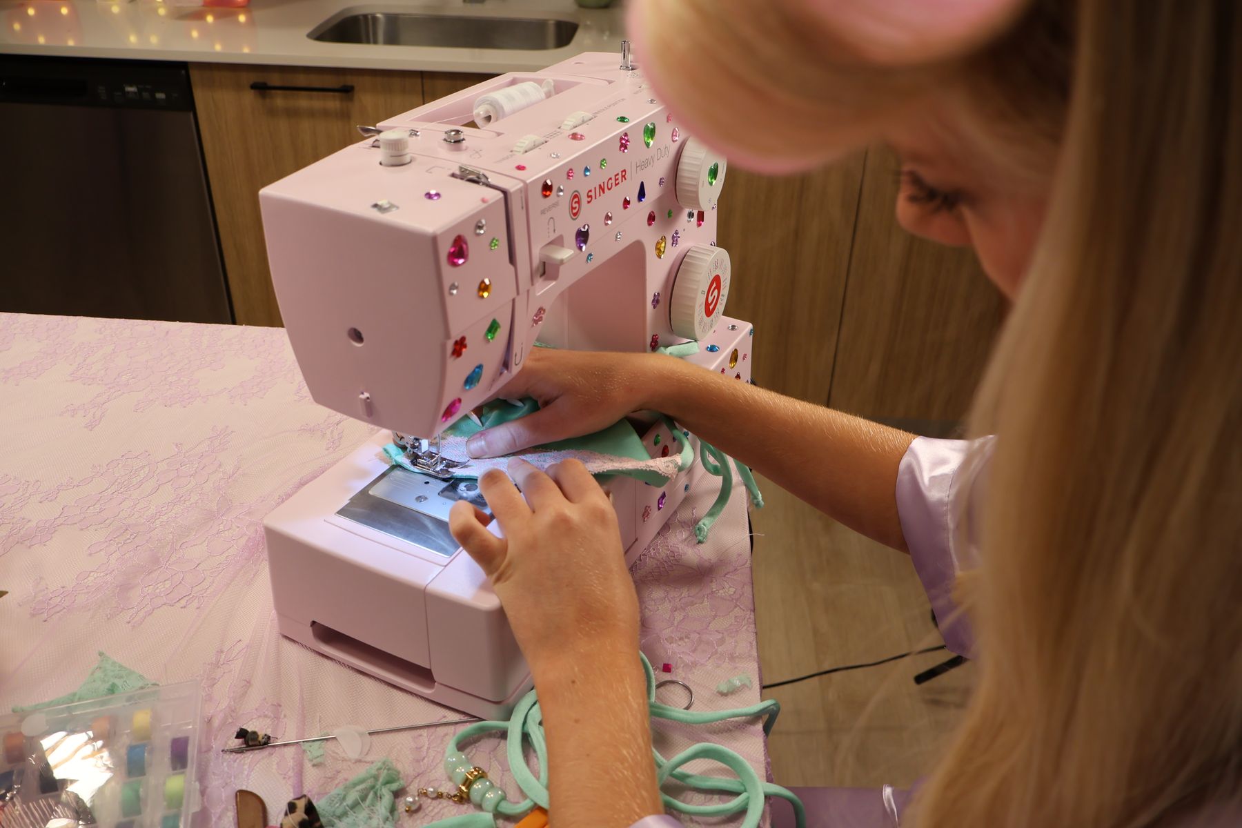 A mint bikini being sewn on a pink jeweled sewing machine
